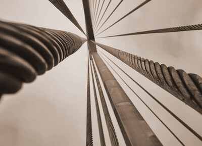 several steel cables stretch toward the sky, the photo is sepia-toned