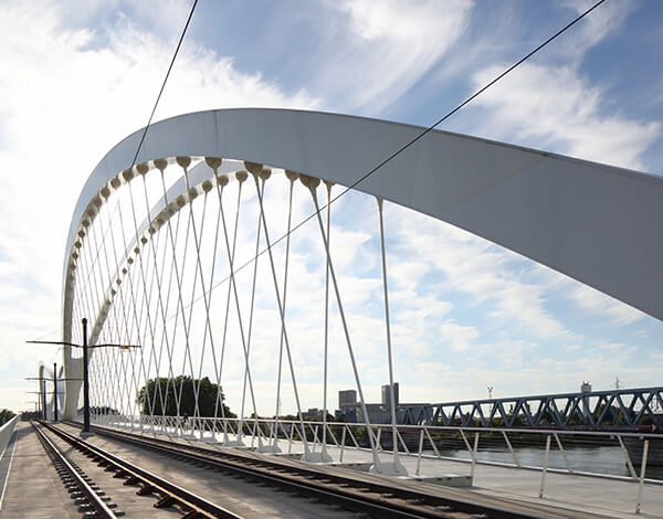 Modern arched railway bridge supported by a network of slender steel cables.